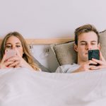 Couple using smartphones bed