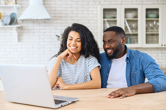 Happy couple talking with others online using a laptop